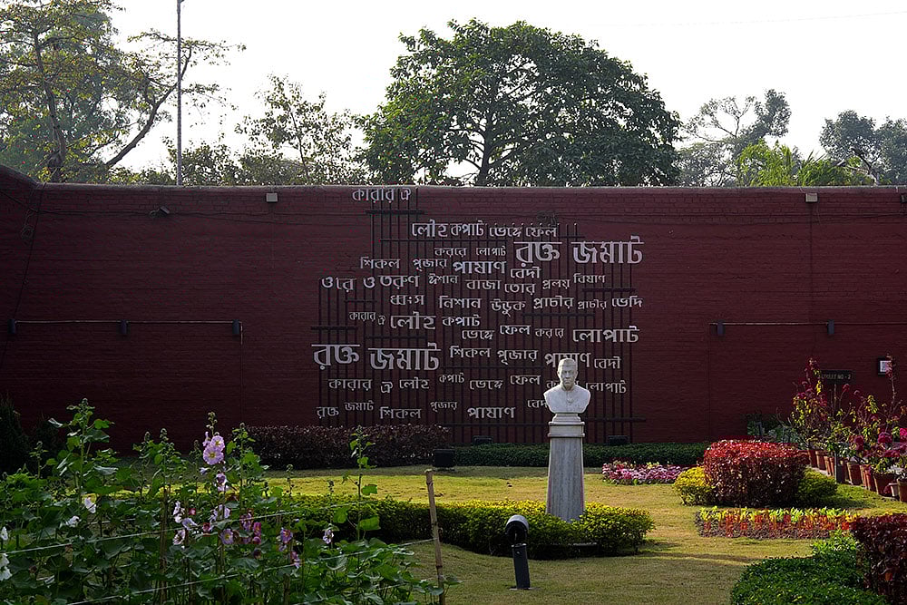 The text on the wall is the first stanza of the famous Bengali poem Karar Oi Louho Kopat by revolutionary poet Kazi Nazrul Islam. In the back drop of Nehru statue in Alipore jail museum. 