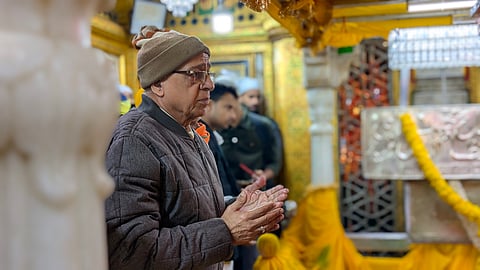 A devotee bows in quiet reverence, hands folded before the saint's tomb in timeless devotion.