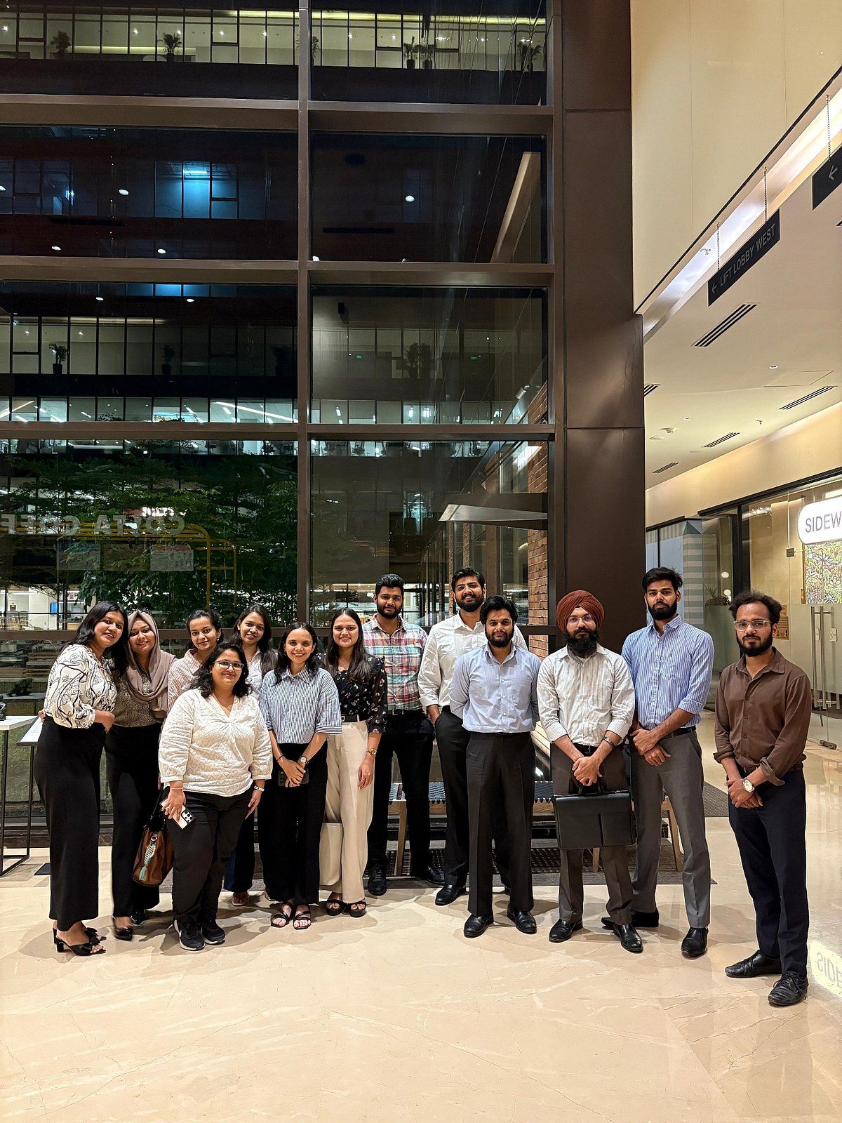  A group of professionals in business attire posing for a picture in a modern office building lobby