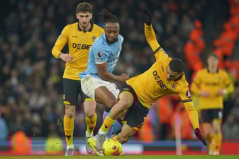 Manchester City's Antoine Semenyo, center tackles Wolverhampton Wanderers' Andre during the English Premier League soccer match between Manchester City and Wolverhampton Wanderers in Manchester, England.