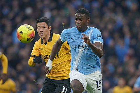 Manchester City's Marc Guehi, right, vies for the ball with Wolverhampton Wanderers' Hwang Hee-chan, during the English Premier League soccer match between Manchester City and Wolverhampton Wanderers in Manchester, England.