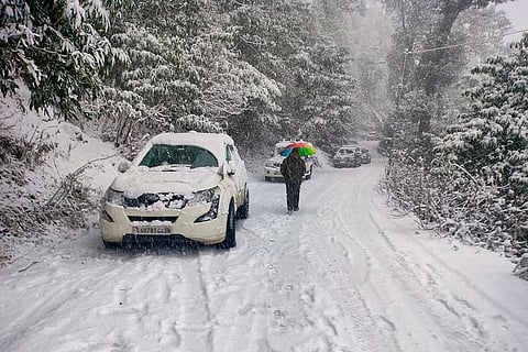 A commuter walks down a road during snowfall, at Joshimath in Chamoli district, Uttarakhand.