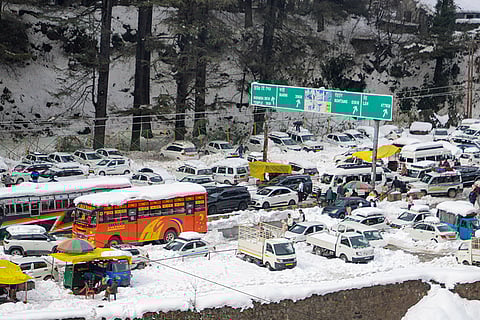 Vehicles remain stuck in a traffic jam as heavy snowfall chokes highways and roads, leaving tourists stranded, near Manali.