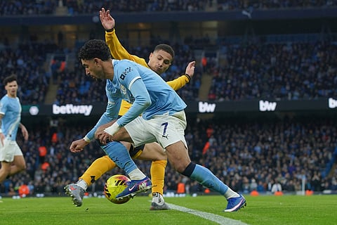 Manchester City's Omar Marmoush, left, is tackled by Wolverhampton Wanderers' Joao Gomes during the English Premier League soccer match between Manchester City and Wolverhampton Wanderers in Manchester, England.