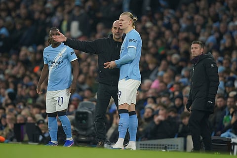Manchester City's head coach Pep Guardiola, center gives instructions to Manchester City's Erling Haaland, right, who is about to come on as a substitute during the English Premier League soccer match between Manchester City and Wolverhampton Wanderers in Manchester, England.