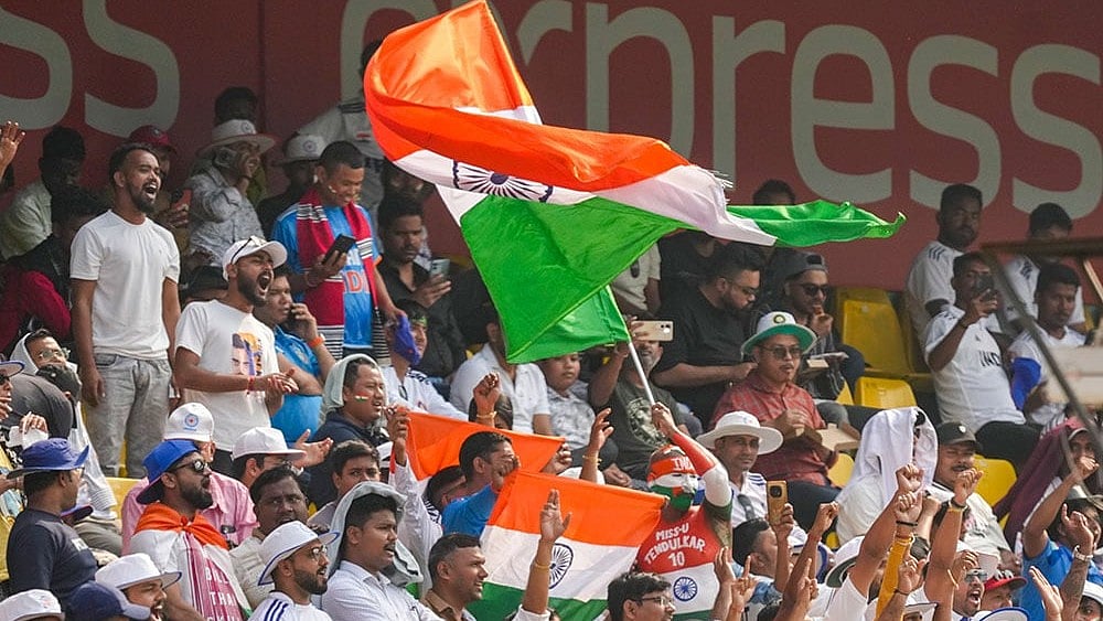 Fans wave the national flag during the day two of the second Test cricket match of a series between India and South Africa, at ACA Stadium in Guwahati. - Photo: PTI/Shahbaz Khan