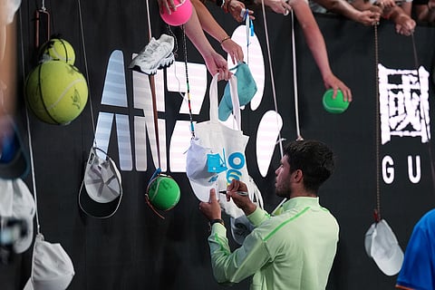 Carlos Alcaraz of Spain signs autographs after defeating Alex de Minaur of Australia during their quarterfinal match at the Australian Open tennis championship in Melbourne, Australia.
