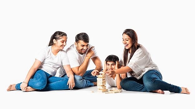 Smiling family of four playing a wooden block stacking game on the floor