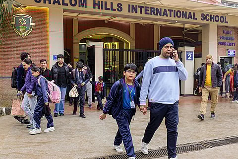 Parents with their children, rush out of Shalom Hills International School after private schools received bomb threats via email, in Gurugram.