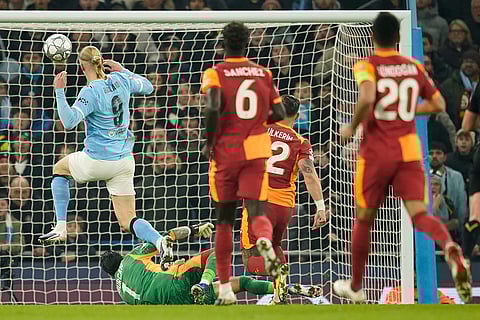 Manchester City's Erling Haaland, left, scores the opening goal during the Champions League opening phase soccer match Manchester City and Galatasaray in Manchester, England.