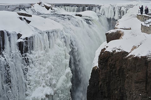 People look over the partial frozen Great Falls in Paterson, New Jersey. 