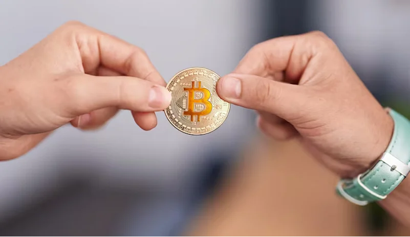 Two hands holding bitcoin coin