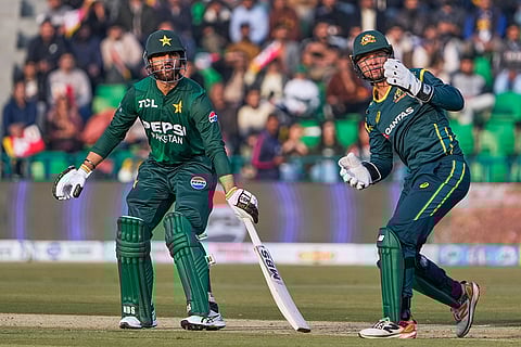 Pakistan's Salman Ali Agha, left, follows the ball after playing a shot as Australia's Josh Philippe watches during the first T20 cricket match between Pakistan and Australia, in Lahore, Pakistan.