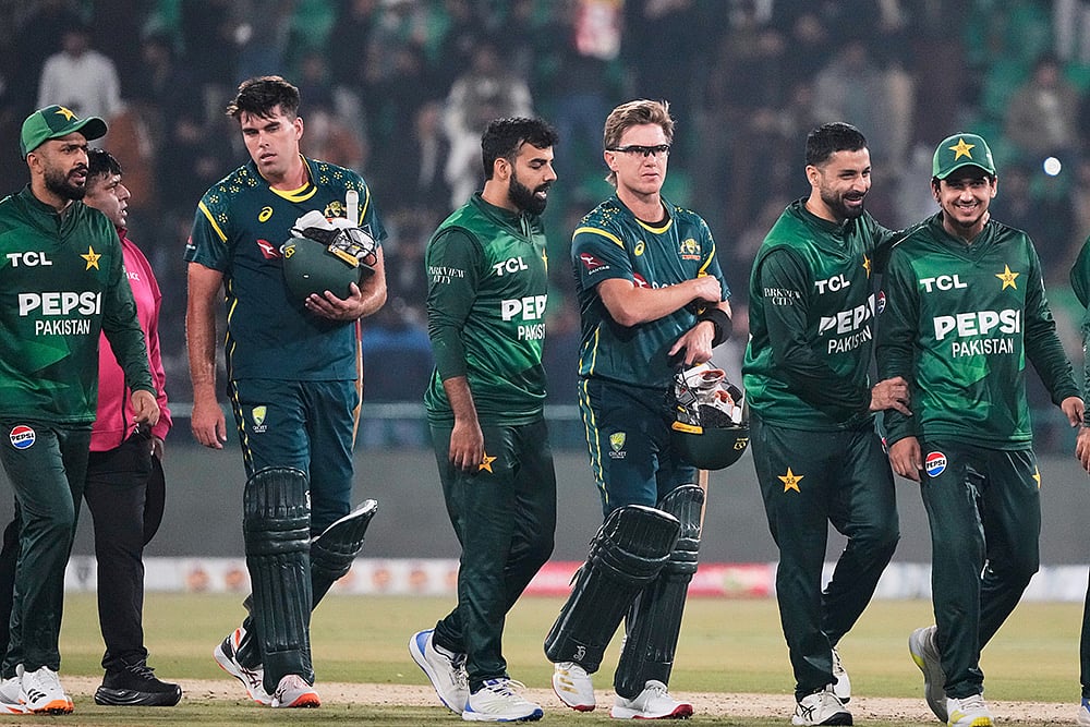 Australia's Xavier Bartlett, second left, and Adam Zampa, third right, and Pakistani players walk off the field on the end of the first T20 cricket match between Pakistan and Australia, in Lahore, Pakistan. - | Photo: AP/K.M. Chaudary