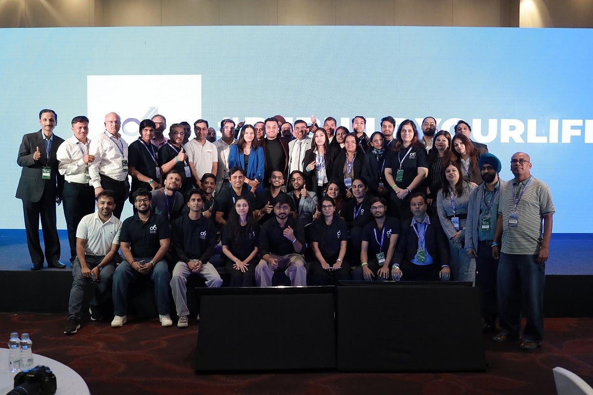 A large group of professionals posing for a photo in front of a blue corporate event banner.