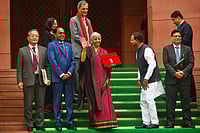 | Photo: AP : Indian Finance Minister Nirmala Sitharaman, center, displays a red folder containing the Union Budget 2026-27 at the steps of the parliament house before tabling it, in New Delhi, India, Sunday, Feb. 1, 2026.