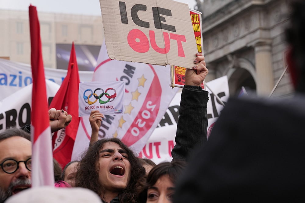 A person holds a sign, during an Anti-ICE demonstration, ahead of the 2026 Winter Olympics, in Milan, Italy. - | Photo: AP/Antonio Calanni