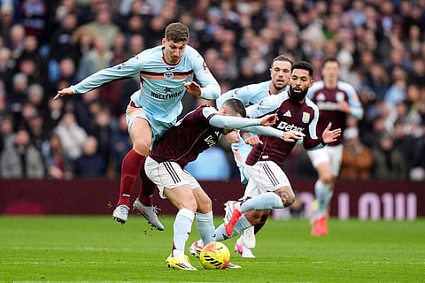 Aston Villa's Emi Buendia, center, and Brentford's Vitaly Janelt battle for the ball during their English Premier League soccer match in Birmingham, England.