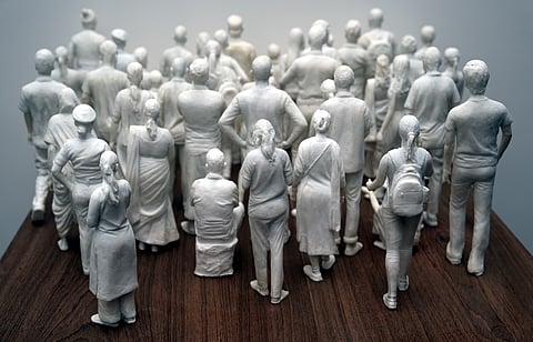 They're ordinary people frozen in every day postures, hands in pockets, carrying bags, facing different ways.