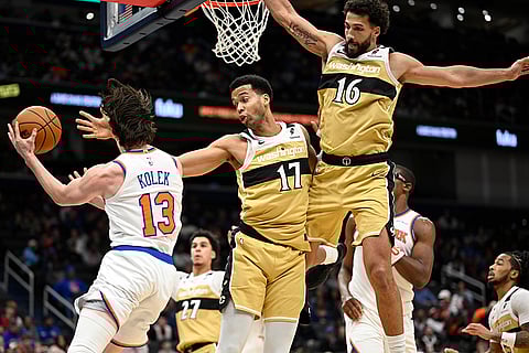 New York Knicks guard Tyler Kolek (13) passes off against Washington Wizards center Skal Labissiere (17) and Wizards forward Anthony Gill during the second half of an NBA basketball game in Washington.