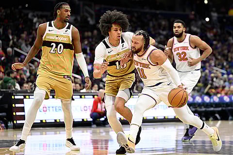 New York Knicks guard Jalen Brunson (11) dribbles down the lane against Washington Wizards forward Kyshawn George during the second half of an NBA basketball game in Washington.