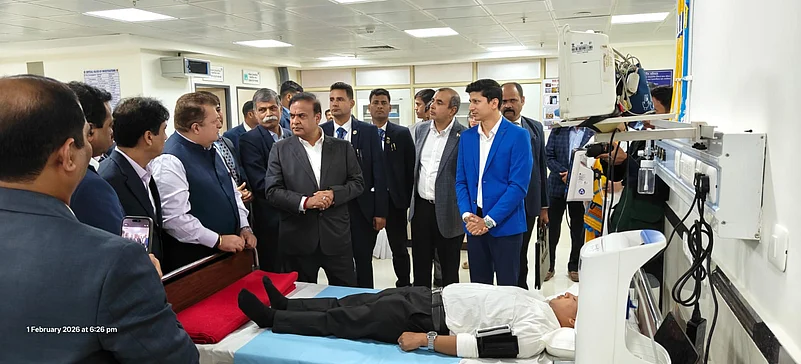 Officials observing medical equipment beside a patient lying on a hospital bed
