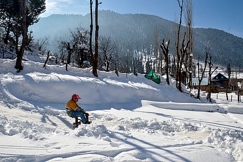 A child slides downhill on a sledge after snowfall at Gawran village, in Anantnag district, Jammu and Kashmir.