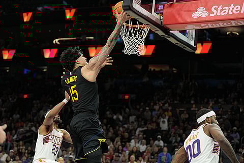 Golden State Warriors forward Gui Santos scores over Phoenix Suns guard Jordan Goodwin and forward Royce O'Neale (00) during the second half of an NBA basketball game in Phoenix.