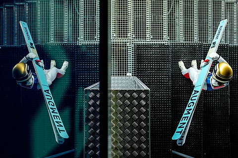 Lisa Eder, of Austria, is reflected on a window while getting ready to jump during a ski jumping, women's normal hill, training session, at the 2026 Winter Olympics, in Predazzo, Italy.