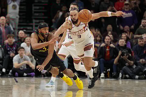 Golden State Warriors guard Moses Moody dives for a loose ball in front of Phoenix Suns forward Dillon Brooks (3) during the second half of an NBA basketball game, in Phoenix.