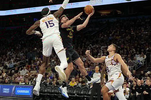 Golden State Warriors guard Pat Spencer (61) drives between Phoenix Suns center Mark Williams (15) and guard Grayson Allen during the second half of an NBA basketball game in Phoenix. 