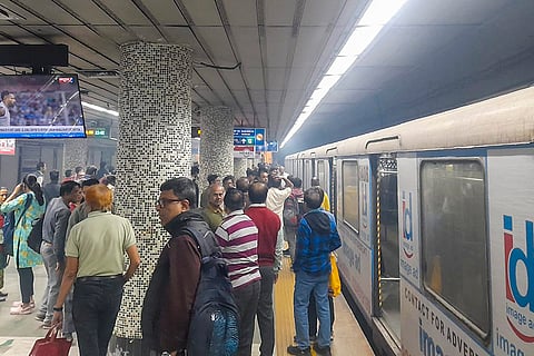 Passengers gather outside a metro train as smoke billows following an alleged electrical fuse in the train, at Esplanade metro station, in Kolkata.