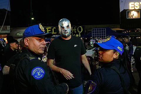 A man wearing a mask of legendary wrestler El Santo waits at a checkpoint before entering to the Arena Mexico in Mexico City.