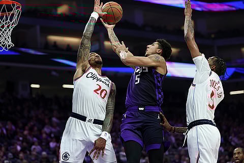 Sacramento Kings guard Nique Clifford, center, goes up to shoot between Los Angeles Clippers forwards John Collins (20) and Derrick Jones Jr., right, during the first half of an NBA basketball game in Sacramento, California.