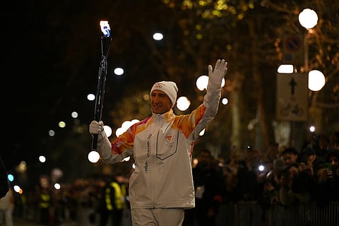 Italy's Enrico Fabris carries the Olympic torch with the Olympic flame  at the Arco della Pace outside the stadium during the Olympic opening ceremony at the 2026 Winter Olympics, in Milan, Italy.