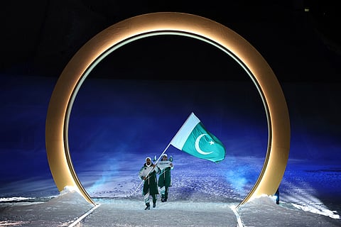 Pakistan's flag bearer Muhammad Karim walks with his teammate during the Olympic opening ceremony at the 2026 Winter Olympics, in Livigno, Italy.