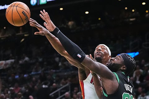 Miami Heat center Bam Adebayo, back, knocks the ball away from Boston Celtics center Neemias Queta, front, during the first half of an NBA basketball game in Boston.