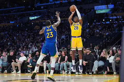 Los Angeles Lakers forward Rui Hachimura (28) shoots for a three-point basket under defense by Golden State Warriors forward Draymond Green (23) during the second half of an NBA basketball game in Los Angeles.