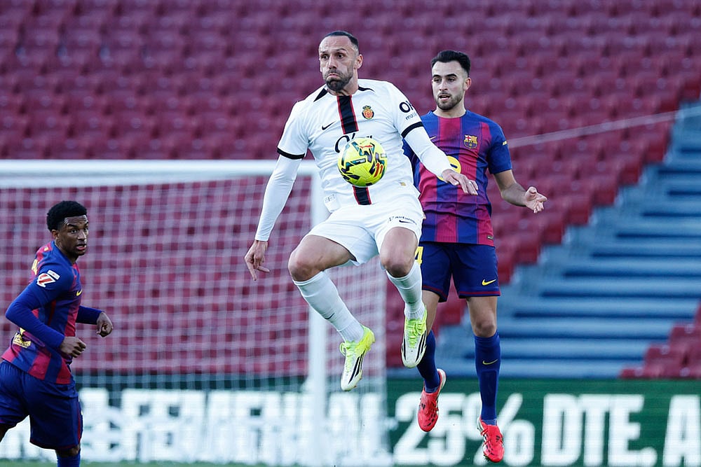 | Photo:AP/Joan Monfort : Mallorca's Vedat Muriqi, front, and Barcelona's Eric Garcia jump for the ball during the Spanish La Liga soccer match between Barcelona and Mallorca in Barcelona, Spain.