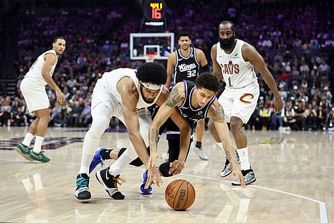 Sacramento Kings guard Nique Clifford (5) and Cleveland Cavaliers center Jarrett Allen, left, dive for a loose ball during the first half of an NBA basketball game in Sacramento, Calif.