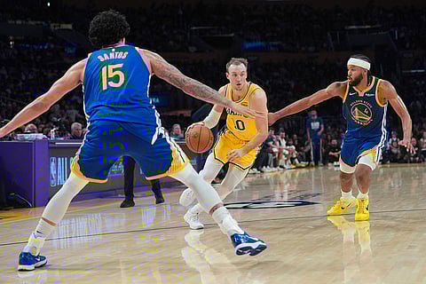 Los Angeles Lakers guard Luke Kennard (10) is pressured by Golden State Warriors guard Moses Moody (4) during the second half of an NBA basketball game in Los Angeles. 
