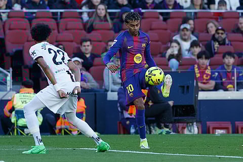 Barcelona's Lamine Yamal, right, passes the ball past Mallorca's Johan Mojica during the Spanish La Liga soccer match between Barcelona and Mallorca in Barcelona, Spain.