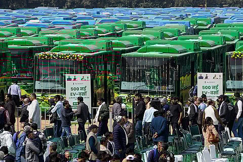 People gather near the buses at an event where Delhi Chief Minister Rekha Gupta, unseen, flagged off 500 new electric vehicle (EV) buses, in New Delhi.