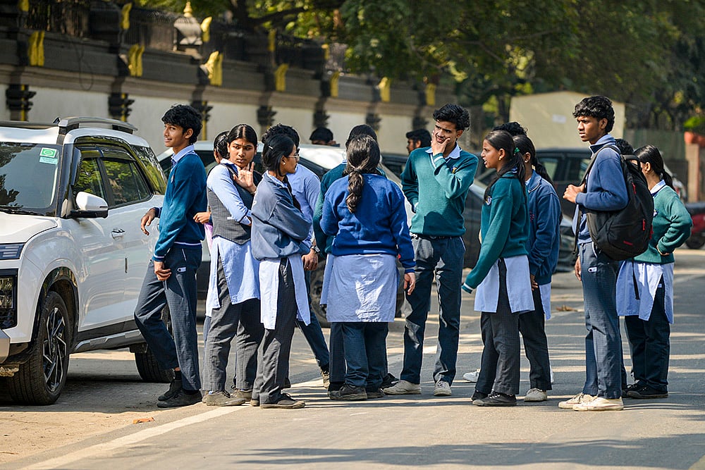 Students stand outside DTA Tamil School after it received a bomb threat, in New Delhi. More than a dozen schools across the national capital received bomb threat emails.  - | Photo: PTI