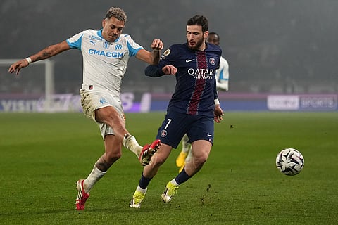 Marseille's Facundo Medina, left, and PSG's Khvicha Kvaratskhelia challenge for the ball during the French League One soccer match between Paris Saint-Germain and Marseille in Paris.