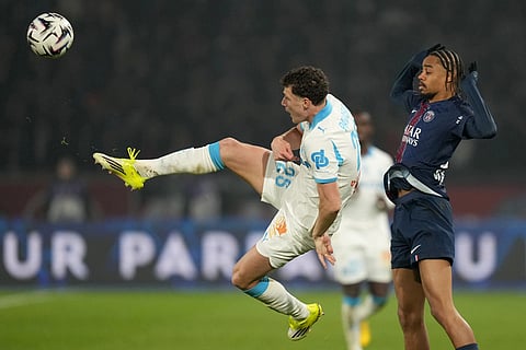 Marseille's Benjamin Pavard, left, and PSG's Bradley Barcola challenge for the ball during the French League One soccer match between Paris Saint-Germain and Marseille in Paris.