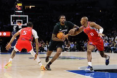 Minnesota Timberwolves center Naz Reid, center, drives to the basket while Los Angeles Clippers guard Kris Dunn (8) and forward Derrick Jones Jr. (5) defend during the first half of an NBA basketball game in Minneapolis. 