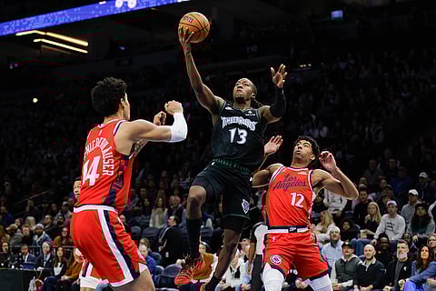 Minnesota Timberwolves guard Ayo Dosunmu (13) goes up to shoot while Los Angeles Clippers center Yanic Konan Niederhauser (14) and guard Cam Christie (12) defend during the first half of an NBA basketball game in Minneapolis. 