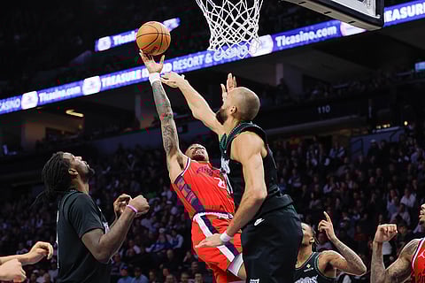 Los Angeles Clippers forward John Collins, center left, goes up to shoot while Minnesota Timberwolves center Rudy Gobert, center right, defends during the second half of an NBA basketball game in Minneapolis.
