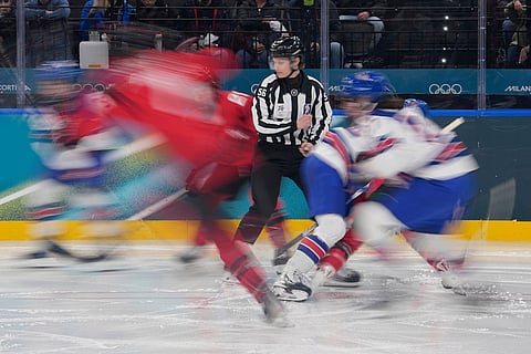 Line judge Sarah Buckner stands as players run during a preliminary round match of women's ice hockey between the United States and Canada at the 2026 Winter Olympics, in Milan, Italy.